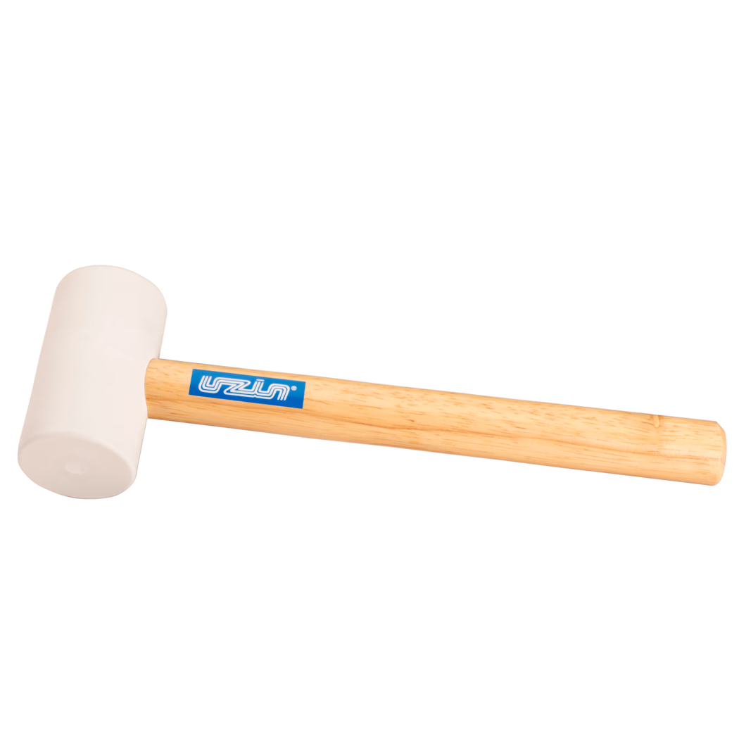 UZIN_Dummy_rubber hammer-UZIN_2014-11 Nahaufnahme eines Gummihammers: ein hellbeiger Gummikopf, der an einem glatten, hellen Holzgriff befestigt ist, mit einem blauen rechteckigen Markenaufkleber; das Werkzeug liegt diagonal auf einem sauberen weißen Hintergrund, weich ausgeleuchtet, sodass die Gummistruktur und die Holzmaserung sichtbar sind; geeignet für schonende Schlagarbeiten beim Holzverarbeiten, Montieren oder Verlegen von Fliesen.